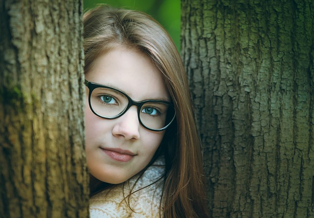 黒縁メガネ　若い女性　木の間から顔を出す