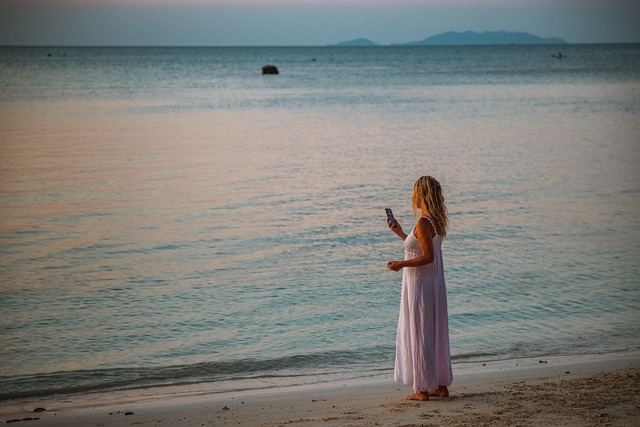 海でスマホを手に持っている女性