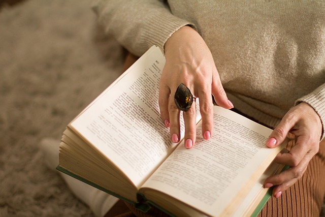 本を読む　薄ピンクのネイル　大きい石の指輪